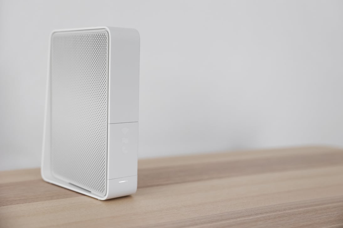 Modern White Wi-Fi Router on Table near Light Wall